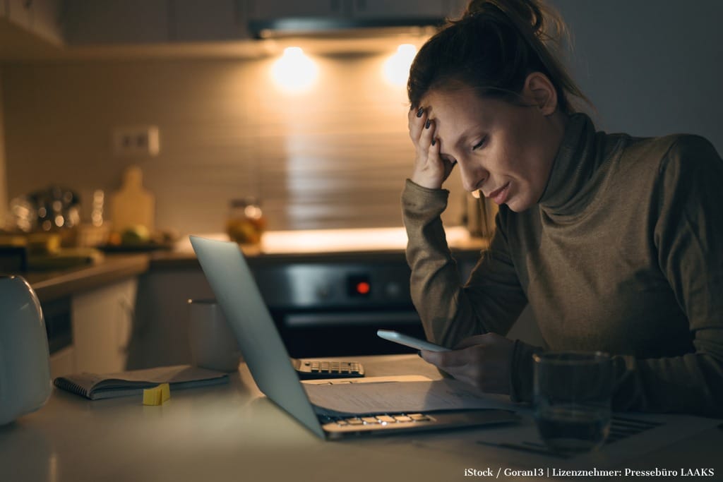 Bild zum ViewMed-Artikel "Stress und Erschöpfung: Wie berufsbegleitende Ansätze helfen können". Zu sehen: Frau am Küchentisch vor Laptop: traurig, gernevt