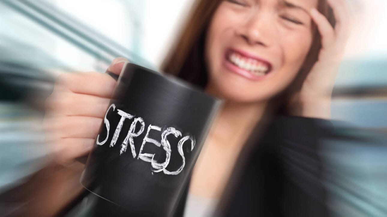 Bild zum ViewMed-Blogbeitrag "10 frühe Anzeichen von Burnout: wie Sie rechtzeitig handeln können ". Zu sehen: Frau mit Kaffeetasse und gestresstem Gesichtsausdruck