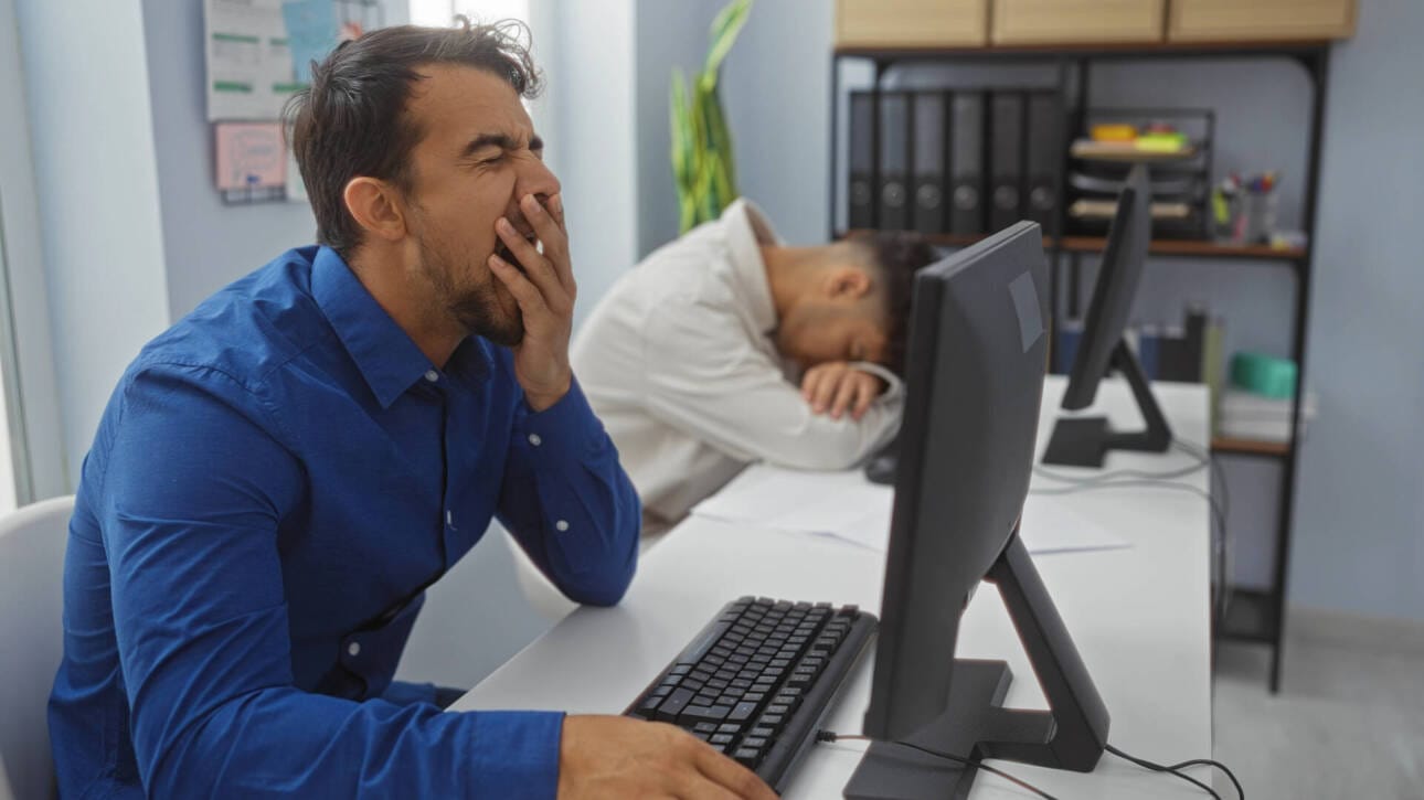 Gähnender Mann vor PC