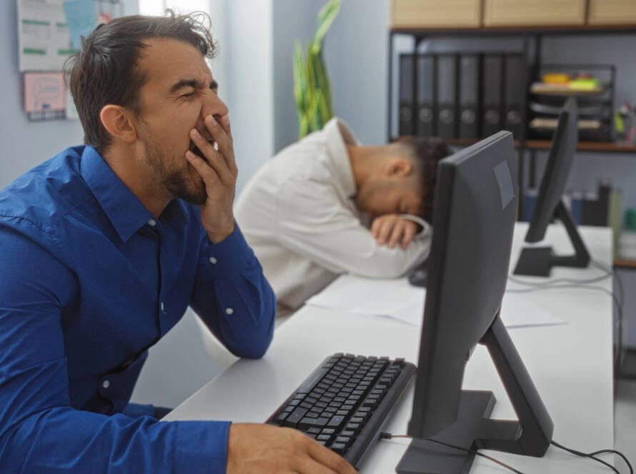 Gähnender Mann vor PC
